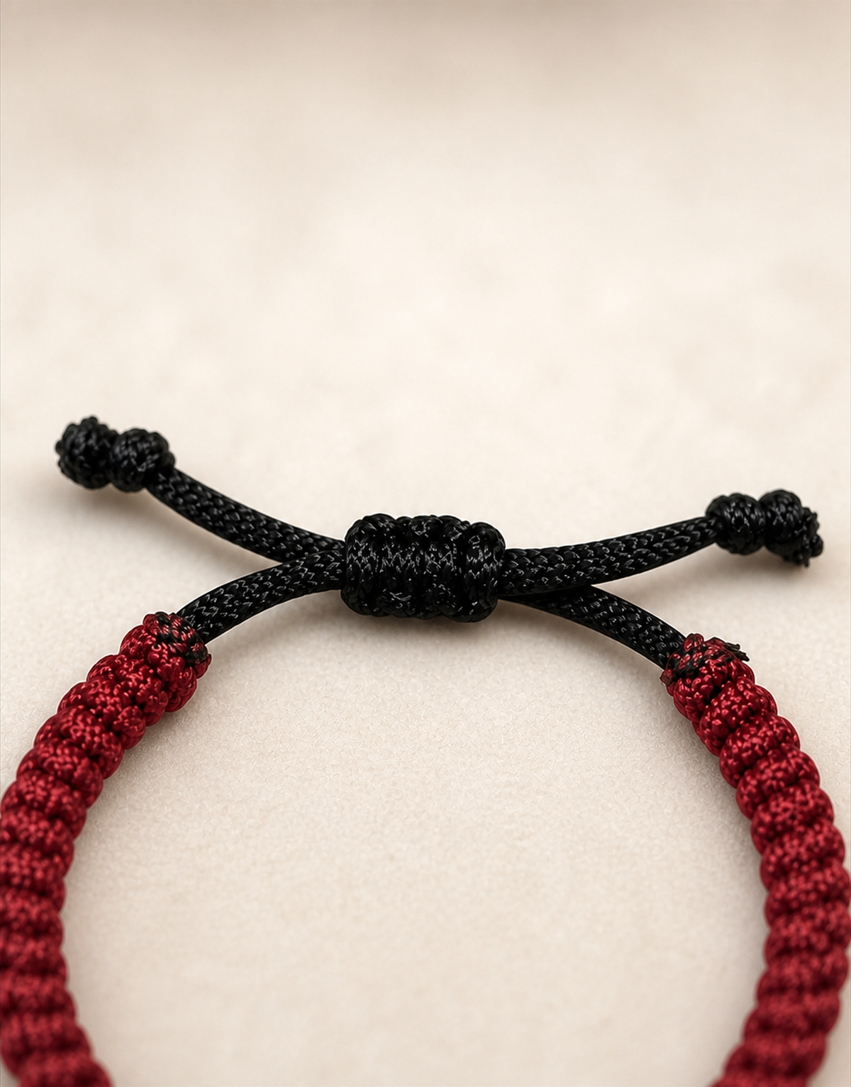 Close-up of a black sliding knot closure on a red handmade macramé bracelet by Giraa