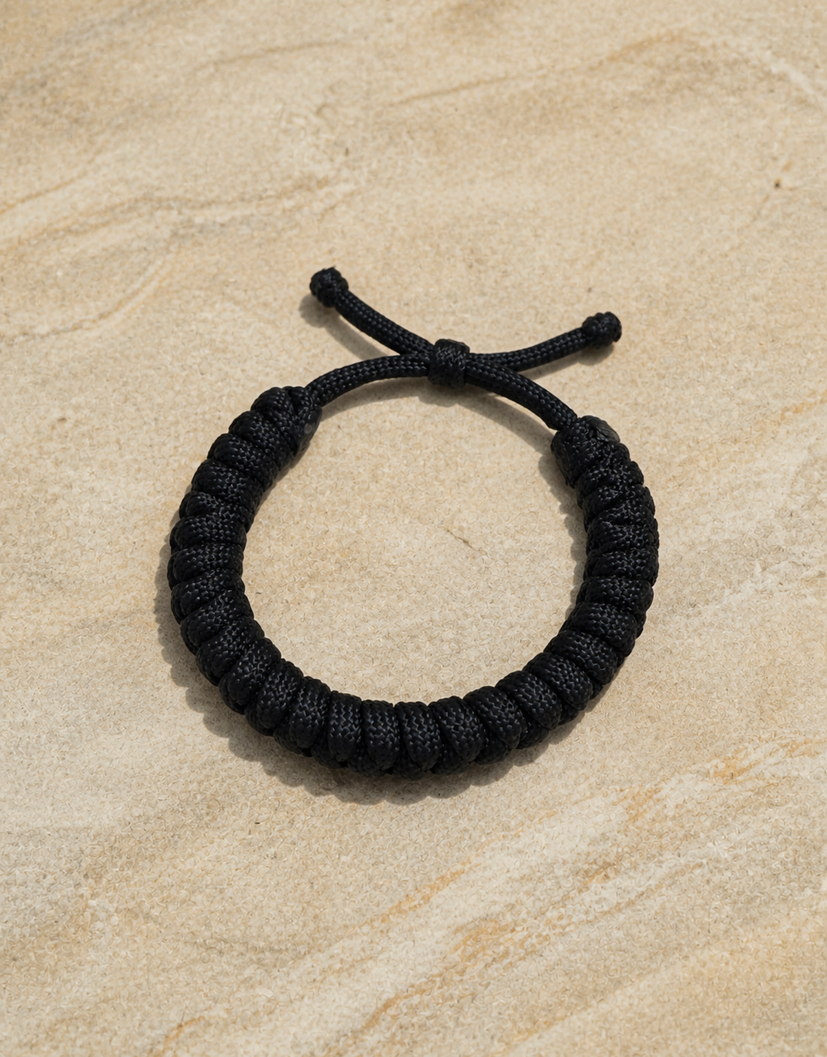 Su'ban black paracord bracelet on sandstone