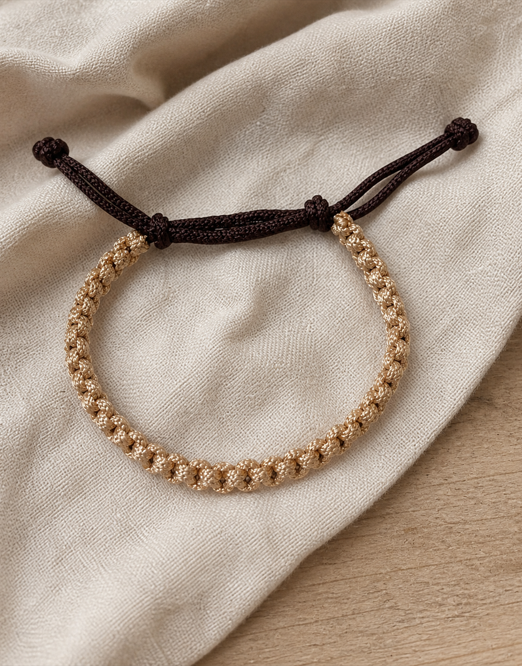 Qamhi tan and brown cord bracelet on linen fabric