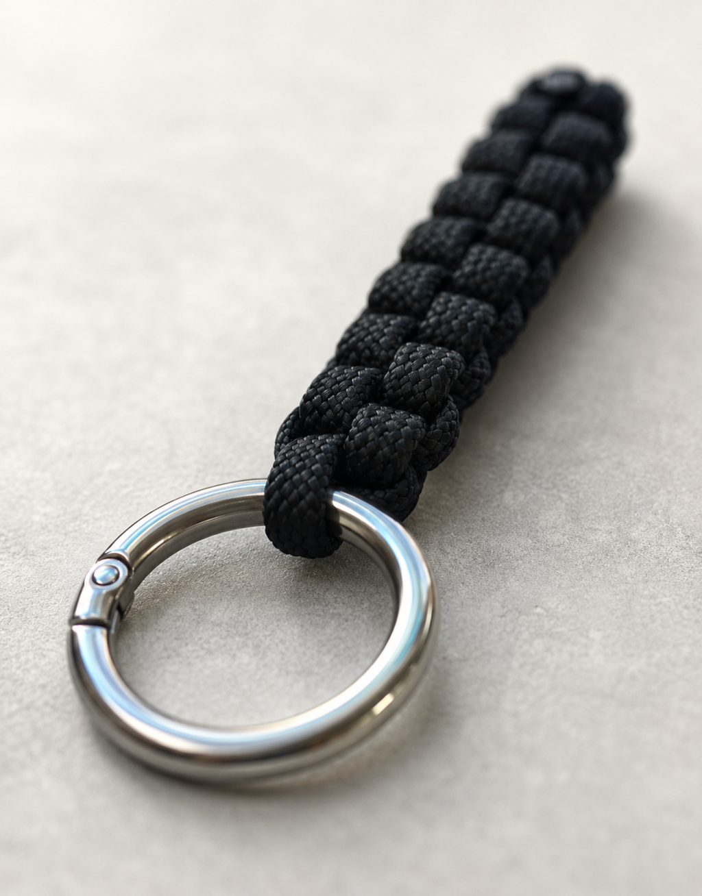 Saf black box weave paracord keychain on a light stone surface