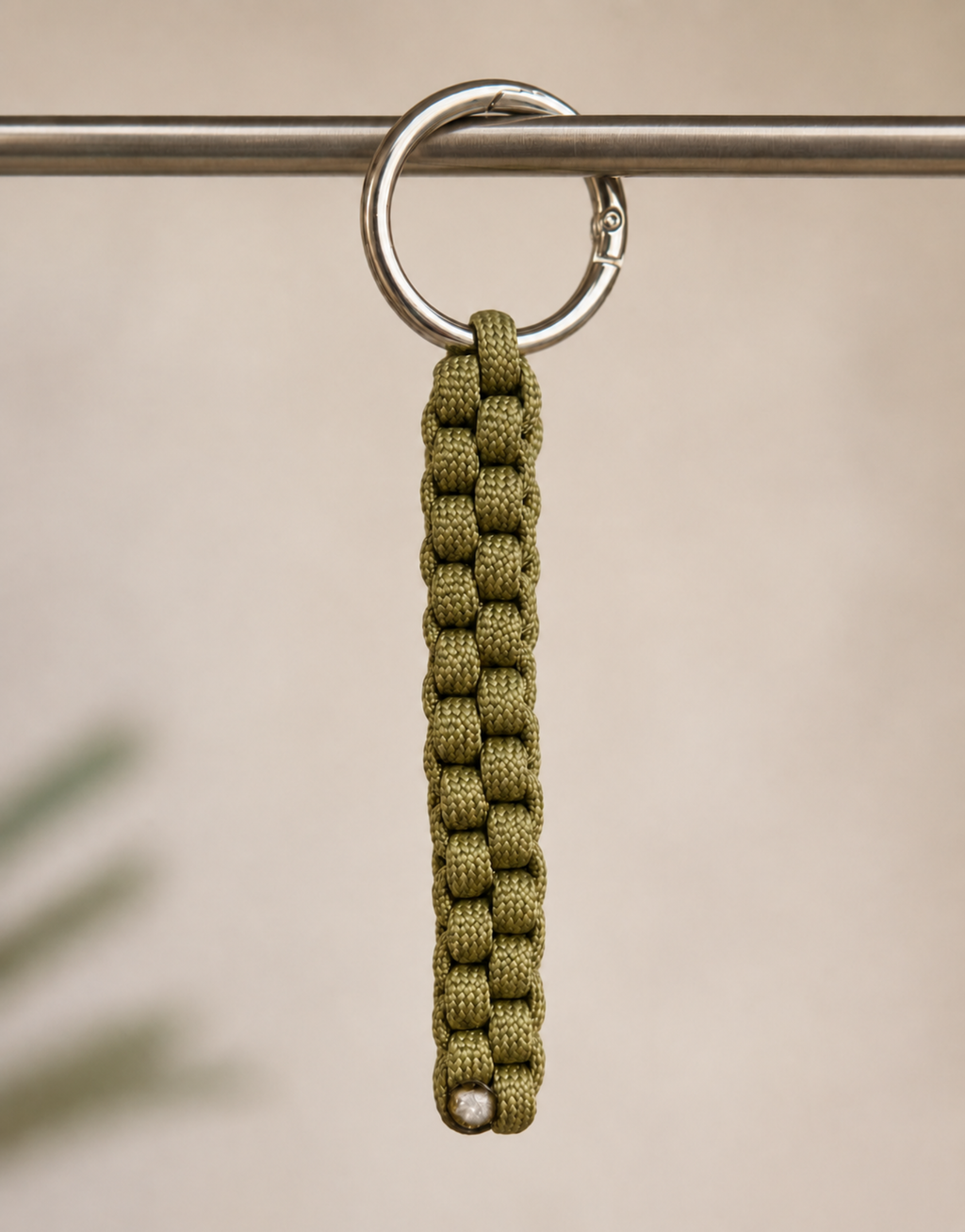 Saf olive box weave paracord keychain hanging from a rail