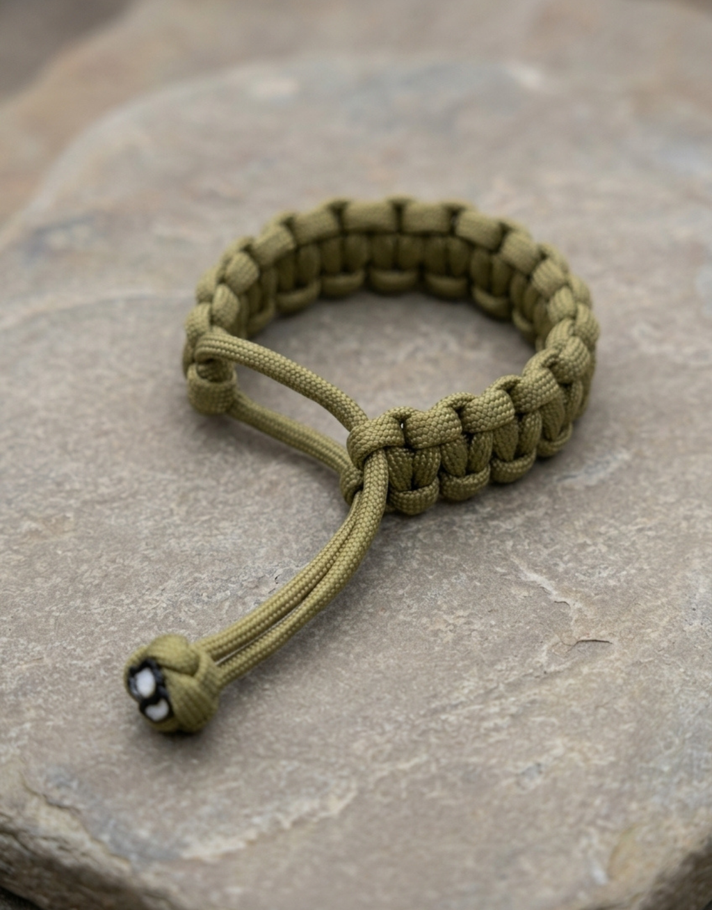 Zeytoon men's olive paracord bracelet resting on a stone slab