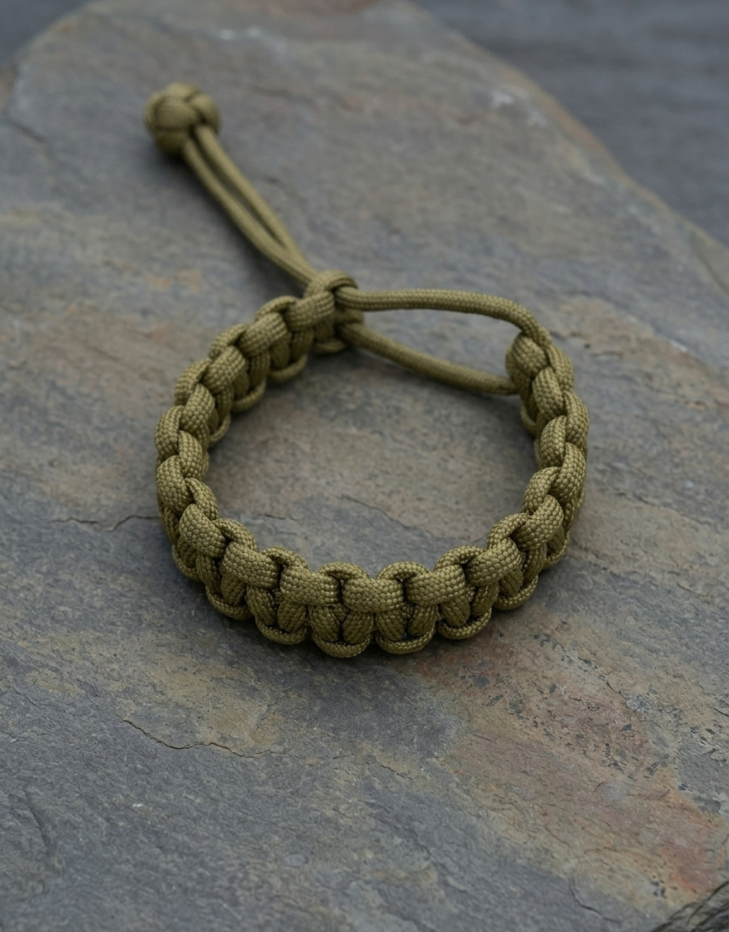 Handmade olive paracord bracelet by Giraa on grey slate