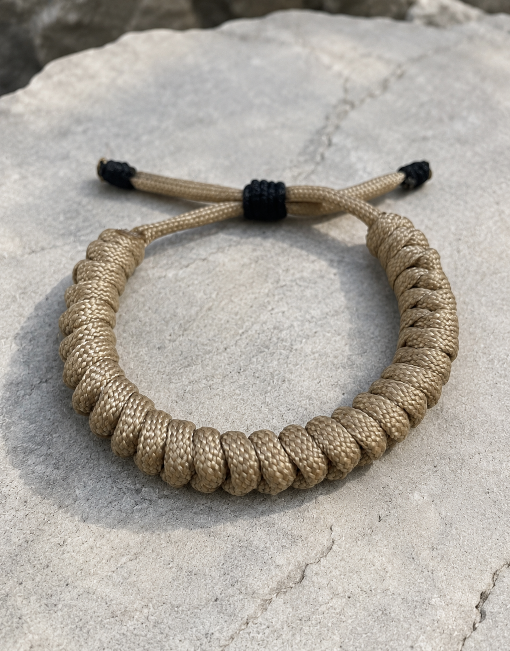 Raml sand spiral paracord bracelet on a grey rock