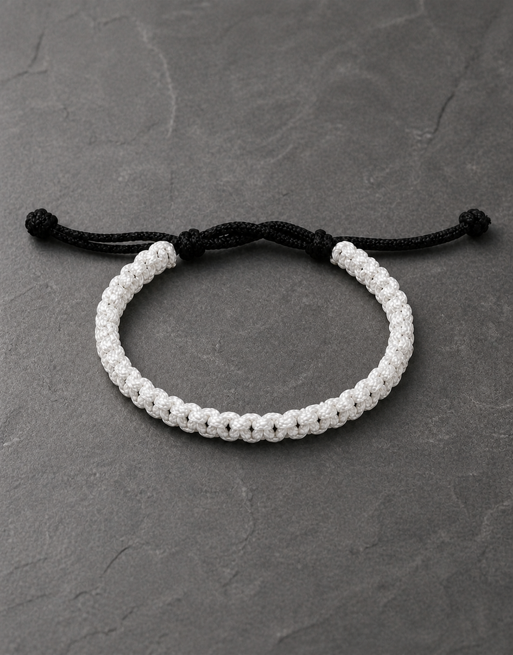 Qamar white macrame bracelet with black closure on dark slate