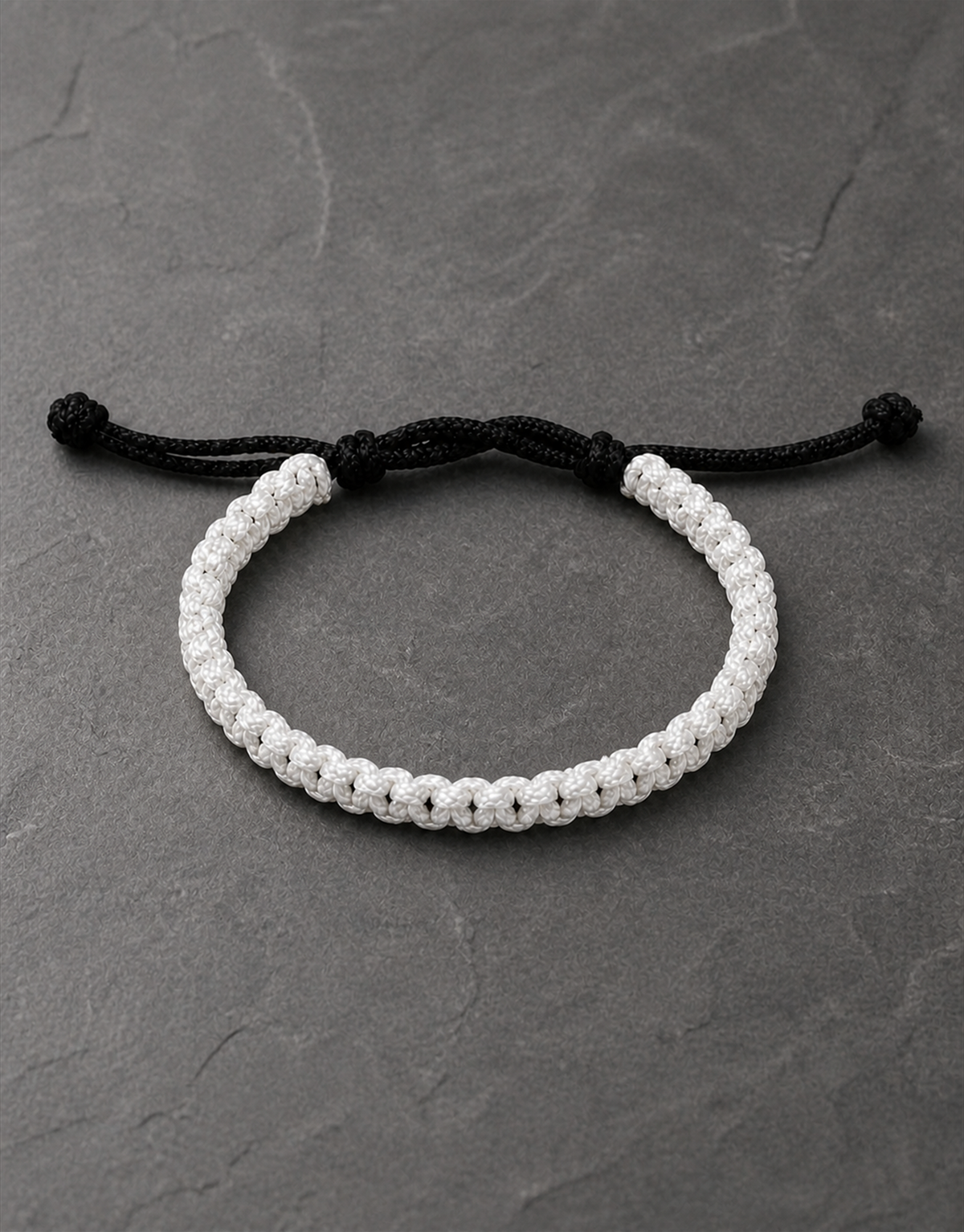 Qamar white macrame bracelet with black closure on dark slate