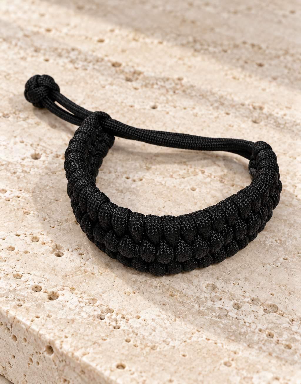 Musallas black paracord bracelet on travertine