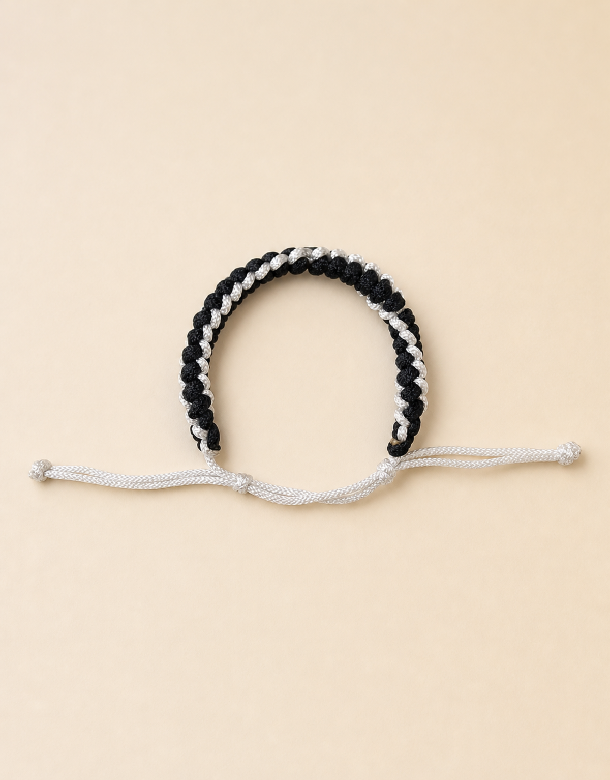 Shatranj black and white cord bracelet on a cream background