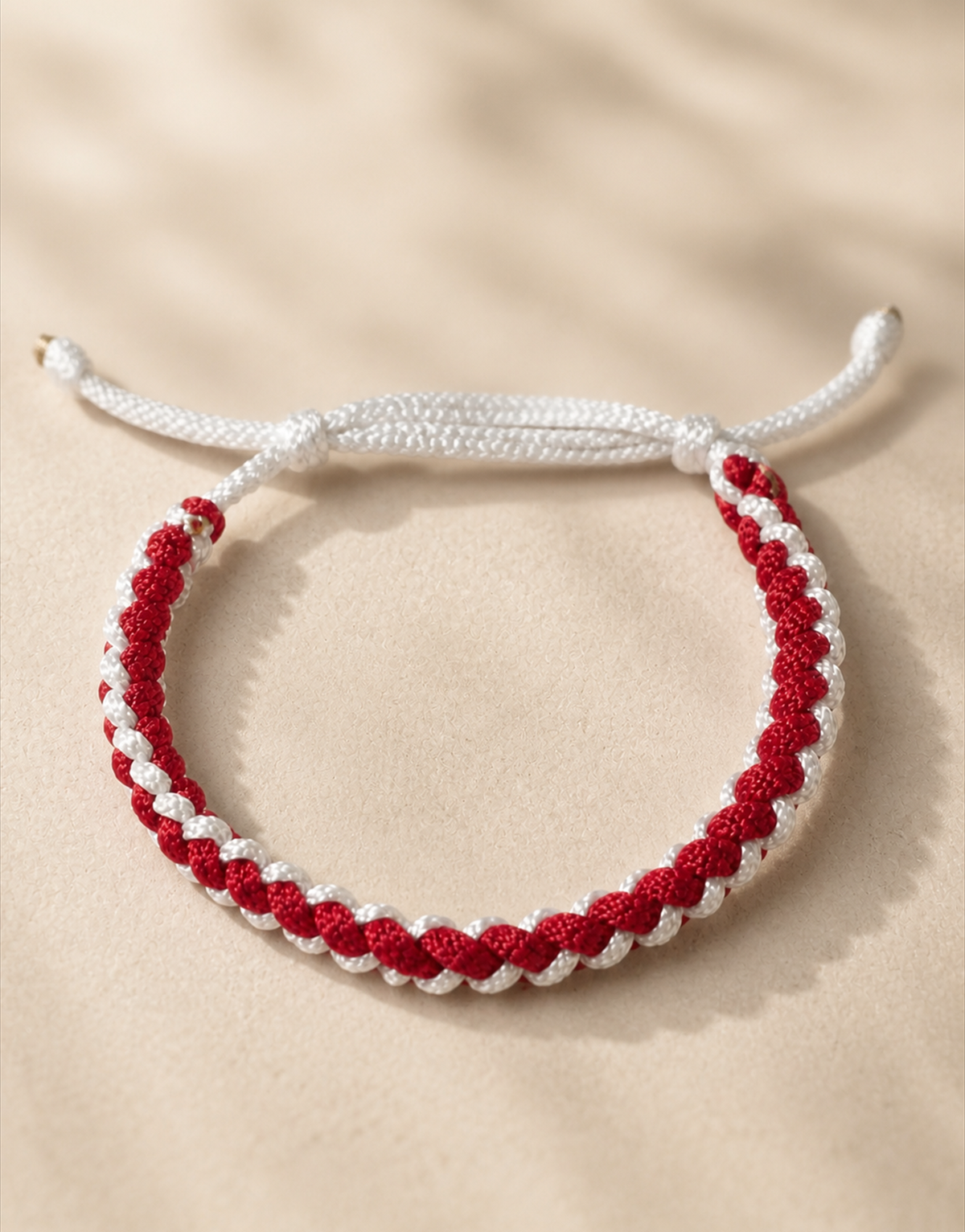 Anaar red and white macrame bracelet on cream fabric