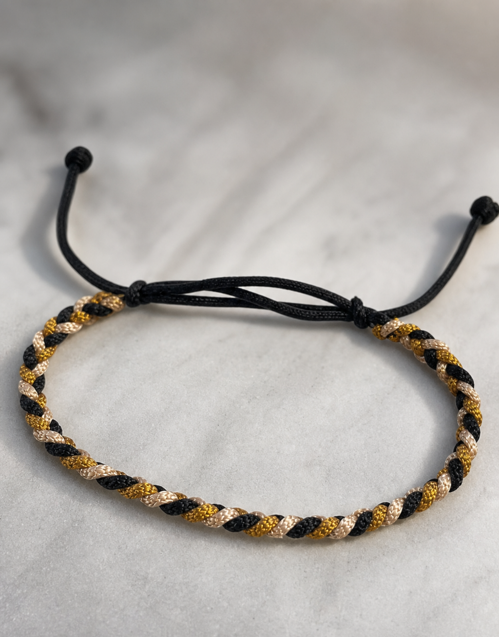 Zari black and gold macrame bracelet on grey linen