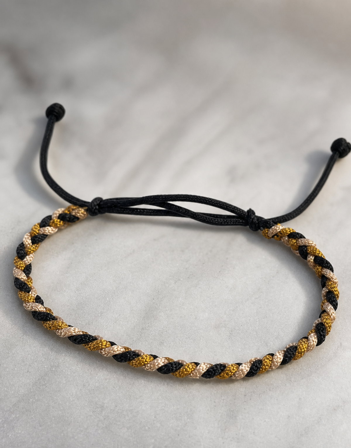 Zari black and gold macrame bracelet on grey linen