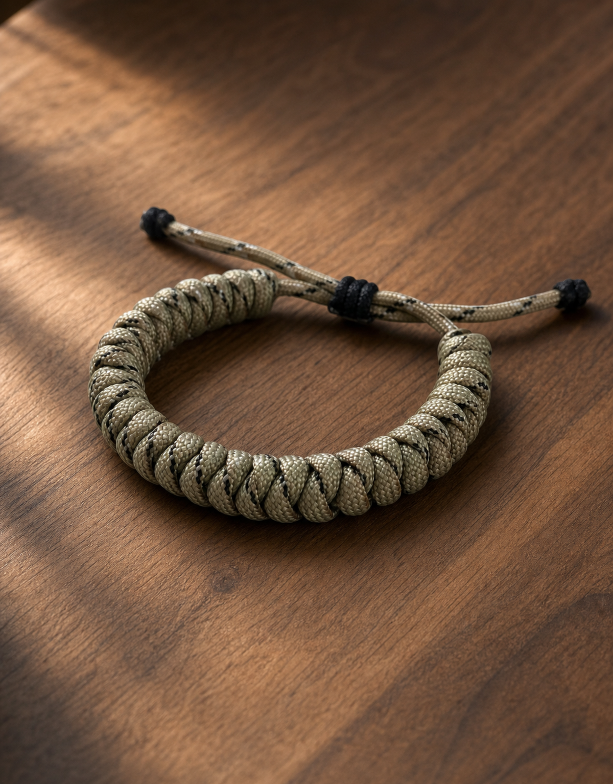 Ramad sand and black paracord bracelet on a wooden table