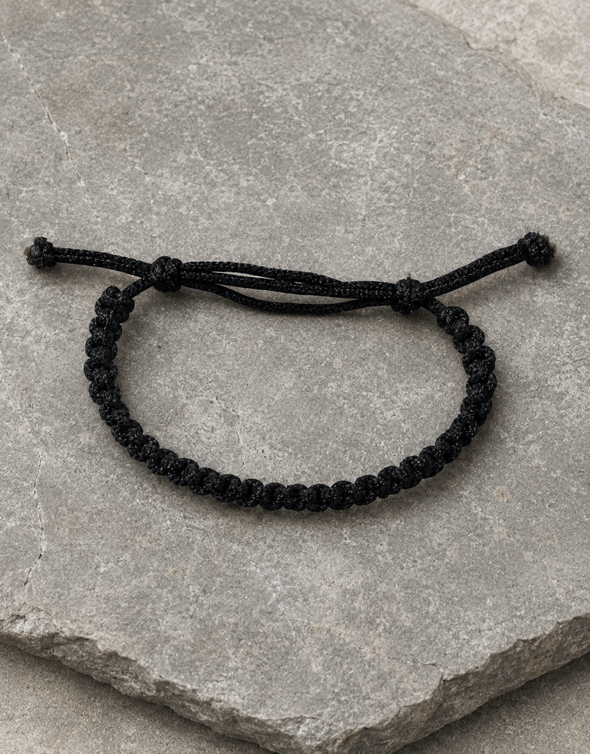 Khayt slim black cord bracelet on a stone slab