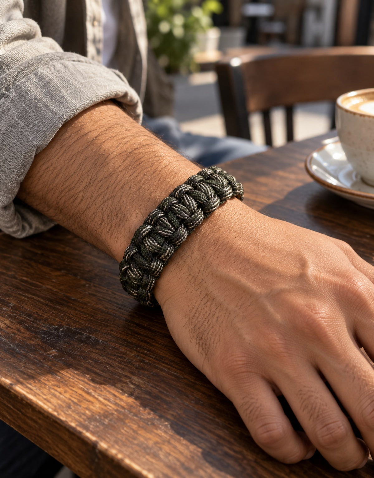 Sipahi camo paracord bracelet worn at a cafe table