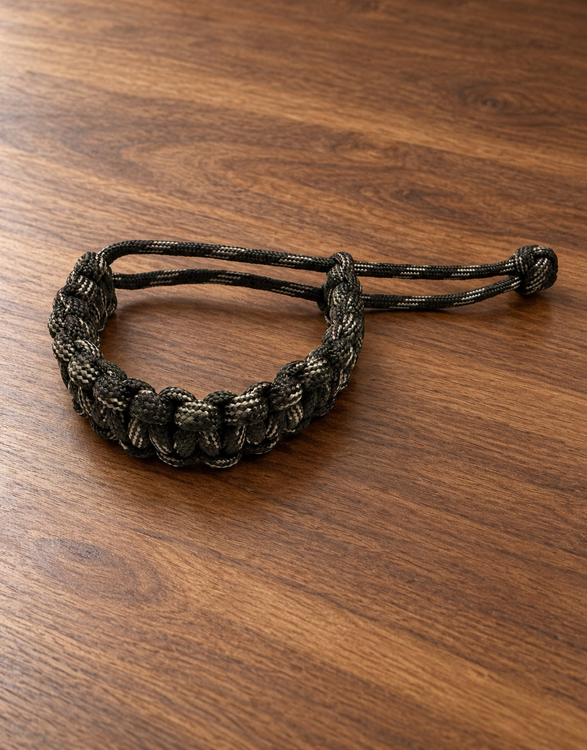 Sipahi dark camo paracord bracelet on a walnut desk