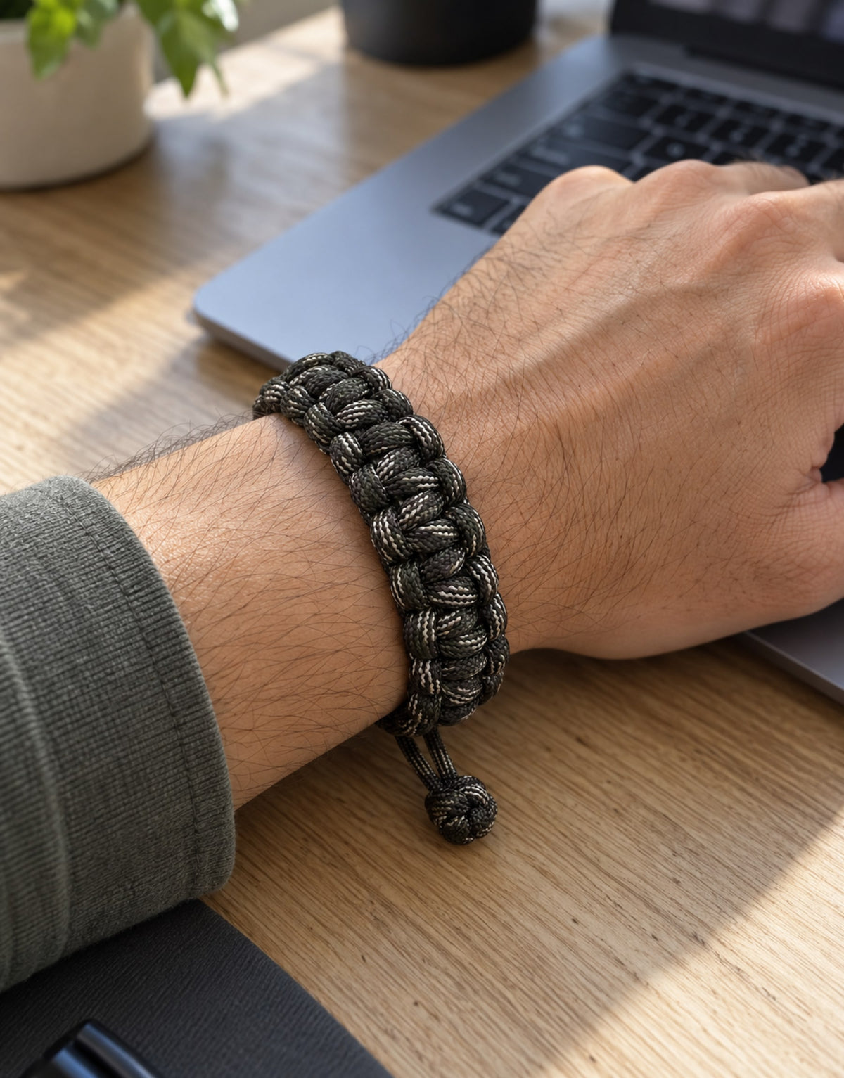 Sipahi camo paracord bracelet on the wrist at a work desk