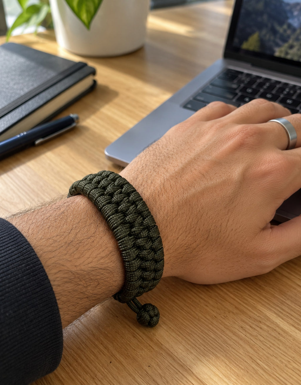 Zirah dark green paracord bracelet on the wrist at a work desk